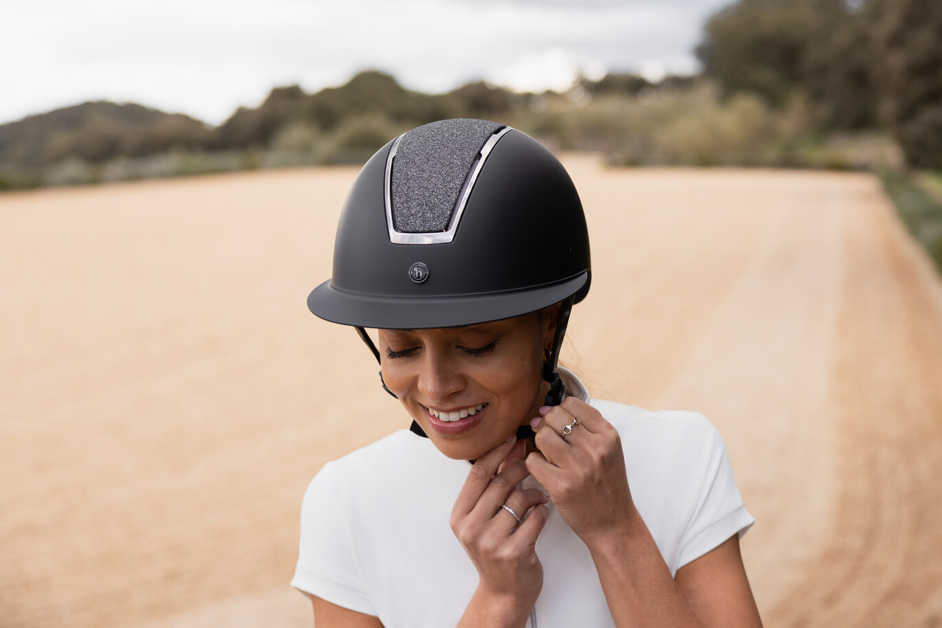 Frau in weißem Reitshirt trägt stilvollen schwarzen Reithelm