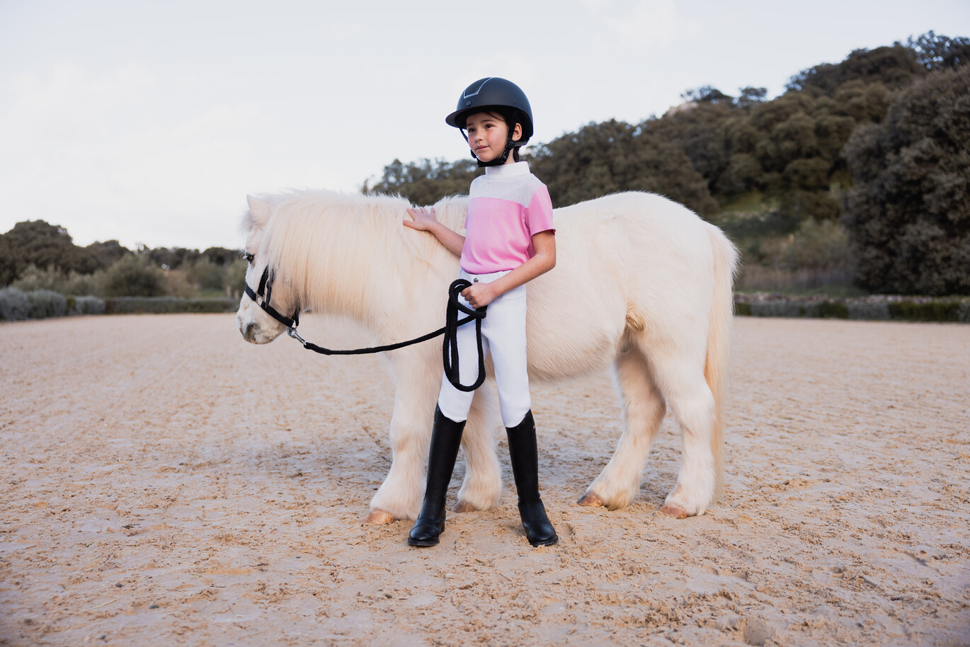 Kind mit Pony und schwarzen Kinderreitstiefeln.